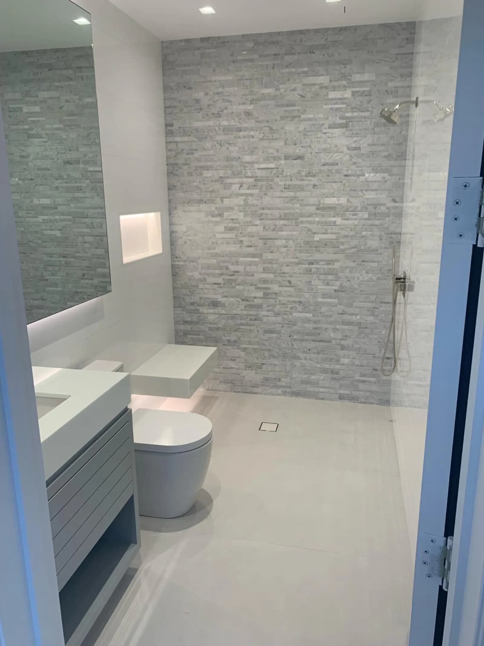 Bathroom with a marble mosaic feature wall, lit niche and floating vanity